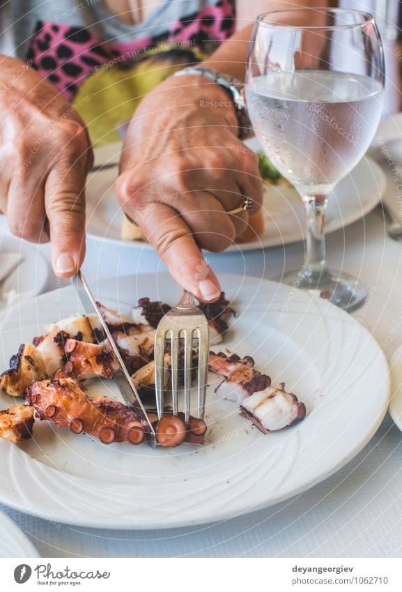 Octopus in a Greek restaurant. Hands are cutting octopus. Seafood Cheese Vegetable Lunch Dinner Diet Plate Table Restaurant Culture Animal Simple Delicious