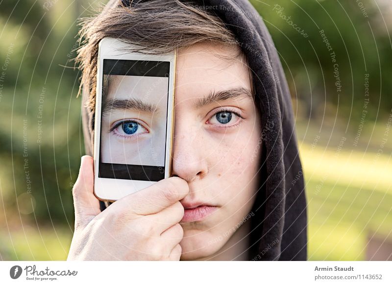 Young man holds a cell phone in front of his eye with a photo of his eye Lifestyle Style Design mobile Technology Telecommunications Human being Masculine