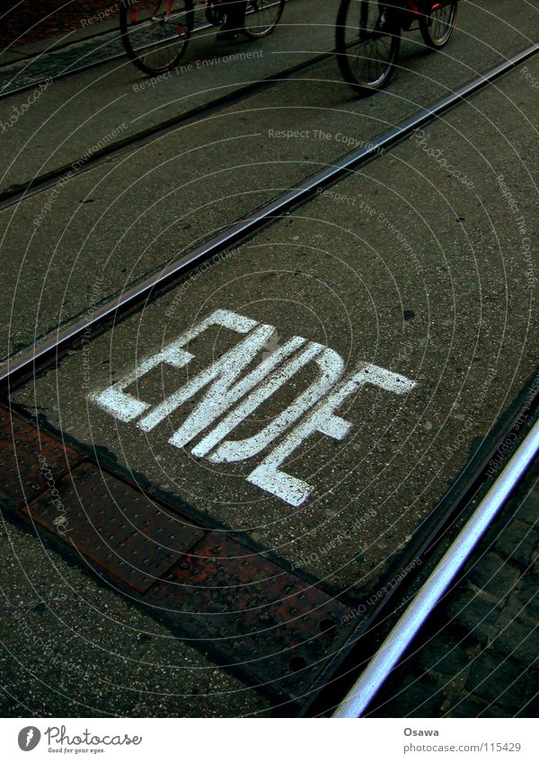 end End Railroad tracks Tram Steel Asphalt Tar Black Gray White Letters (alphabet) Word Information Communication Bicycle Cycle path Dark Glittering Dark gray