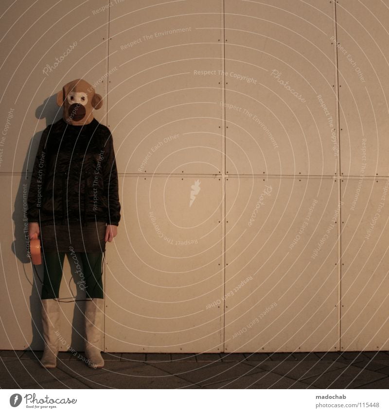 Woman stands with mask on an urban wall and holds a hair dryer in her hand young hipster fashion circus Lifestyle Night life Entertainment Party Event