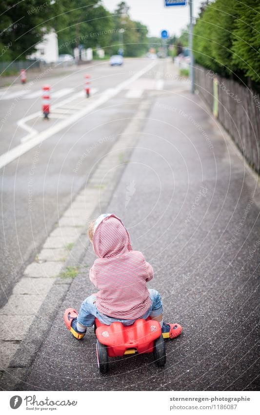 road traffic Bobbycar Child Childhood memory Toddler Car Street Sidewalk Footpath Driving Playing Red Toys Traffic cone Pylon Hooded (clothing)