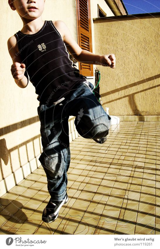 Boy jumps on roof terrace Child 5 Year Undershirt Digits and numbers Floating Fist Concentrate Boy (child) Pallid Brown Sneakers Deep Long Stripe Wall (barrier)