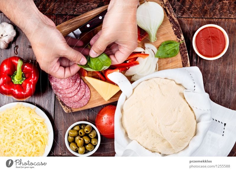 Preparing ingredients for homemade pizza Food Cheese Vegetable Dinner Fast food Bowl Table Hand 1 Human being Leaf Fresh Basil board cuisine dough Garlic