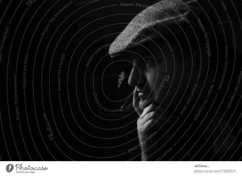 Thoughtful young man with slider cap against black background Man Head Hand sliding cap Peaked cap Dark Black Meditative Rest on Observe Think Profile