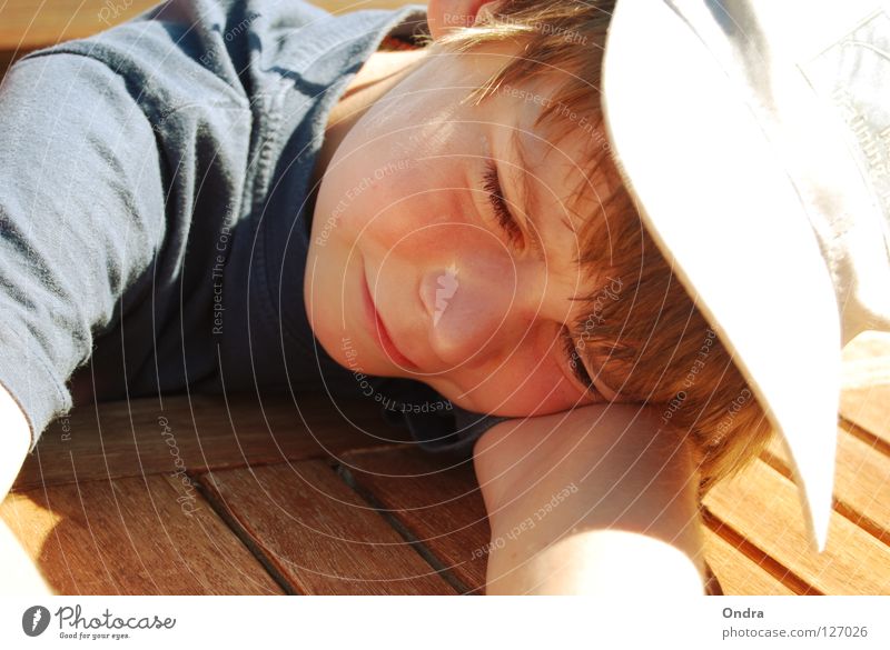 sleeping cap Boy (child) Masculine Child Sleep Slouch Baseball cap Dazzle Summer Wood Table Watercraft Human being Lie Fatigue Relaxation Grinning