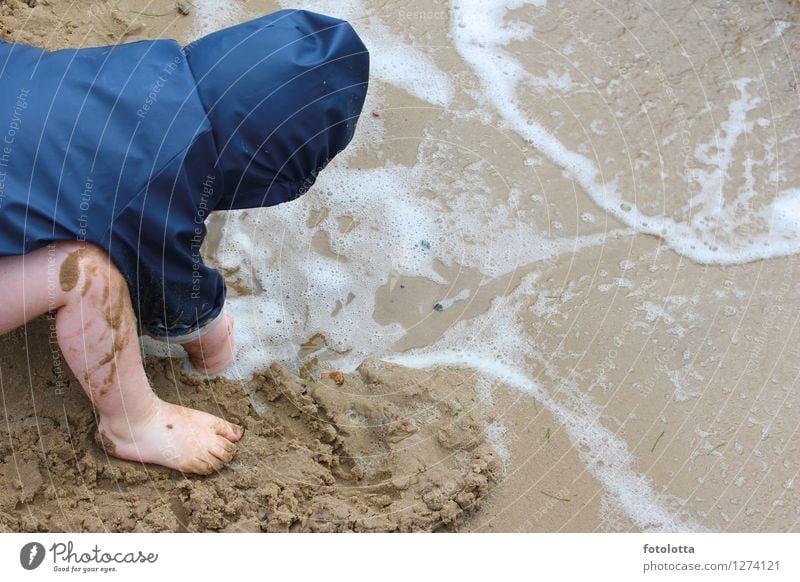 dig Joy Playing Muding Beach Toddler Legs Feet Nature Sand Water Waves River bank Rain jacket Wet Blue Beige slobbery Barefoot Wind Exterior shot Colour photo