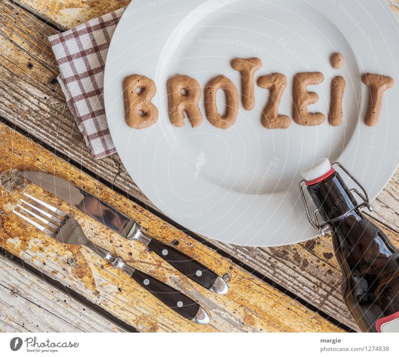 On a rustic wooden table a plate with the letters BREAD TIME, knife and fork, napkin and a bottle of beer Food Bread Brunch Nutrition Lunch Dinner Picnic