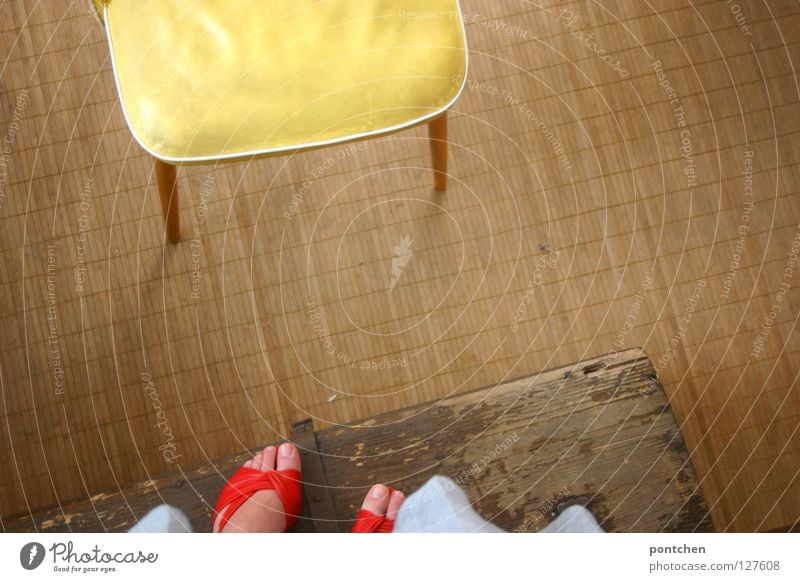 Women's feet in red sandals stand on a wooden box in front of a yellow chair. Distance, distance, height. With, fear Bird's-eye view Playing Children's game