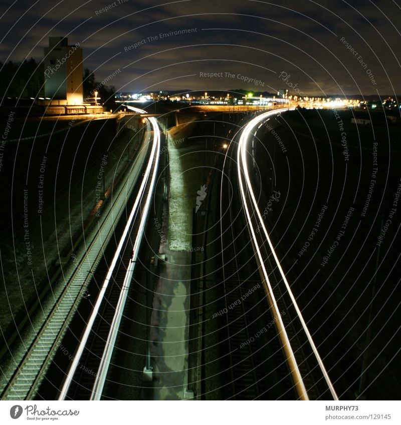 Trains at night Railroad Railroad tracks Night Long exposure Town Silo Freight car Freight train Express train Tracer path Light Clouds Tree Lamp Horizon Gray