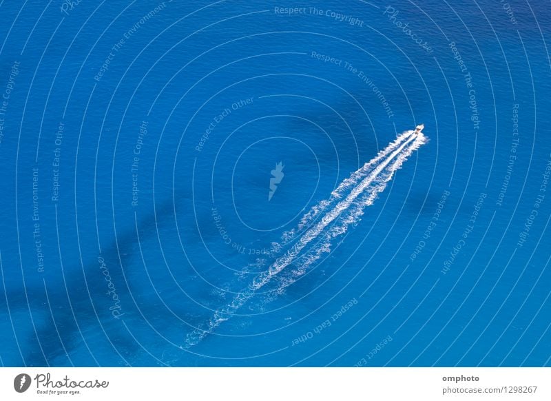 Aerial image of motorboat floating in a turquoise blue sea water. The boat is moving diagonally through the frame of the photo. Vacation & Travel Summer Ocean