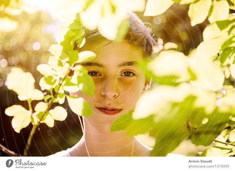 Smiling teenager behind leaves with sun on his back Lifestyle Style Joy pretty Wellness Harmonious Contentment Human being Masculine Young man