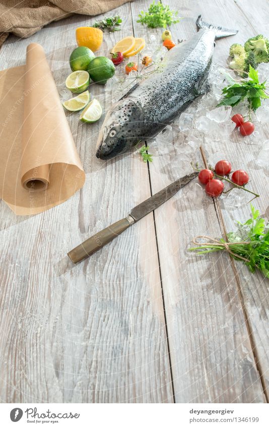 Raw salmon fish in ice and vegetables Seafood Vegetable Dinner Table Cook Paper Fresh Delicious Red White Salmon Lemon Baking paper knife wooden Tomato Broccoli