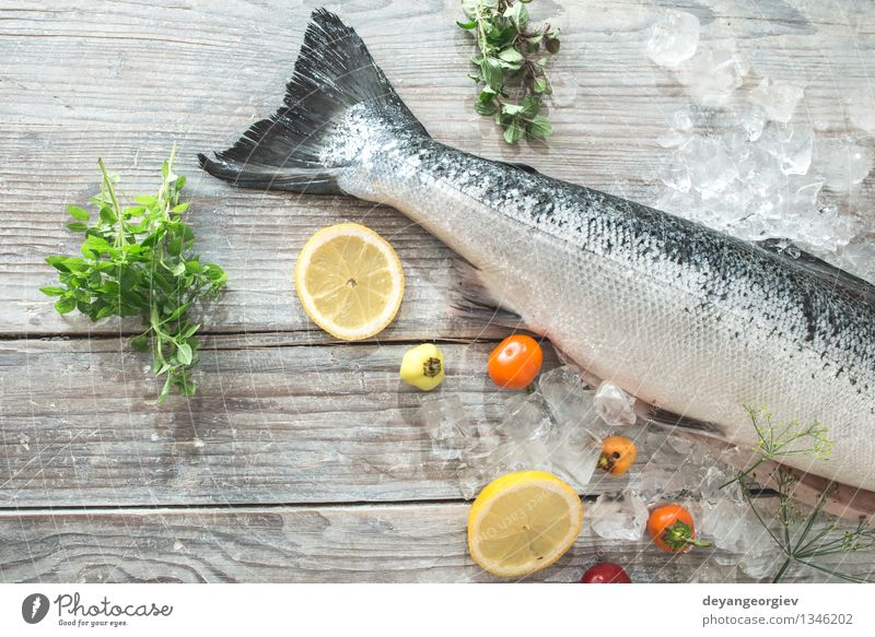 Raw salmon fish in ice and vegetables Seafood Vegetable Dinner Table Cook Paper Fresh Delicious Red White Salmon Lemon Baking paper knife wooden Tomato Broccoli