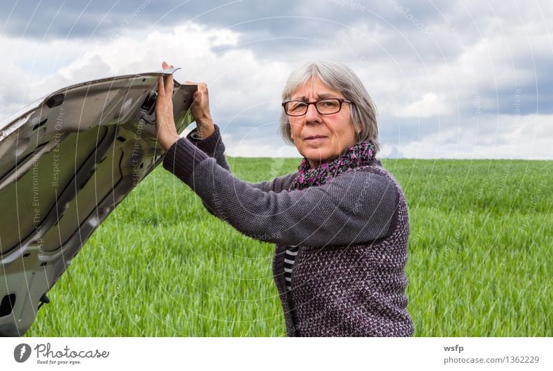 Car has broken down Seniorin opens hood Retirement Woman Adults Female senior Old Broken Concern Stagnating Breakdown Car Hood car breakdown Open engine failure