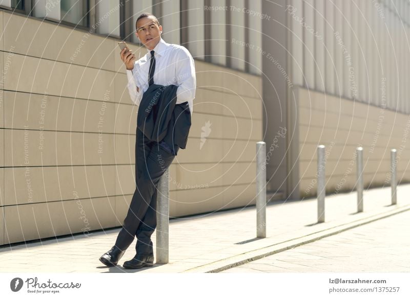 Businessman sitting on a bollard reading an sms Reading Summer Financial Industry Telephone PDA Technology Man Adults Suit Tie Sit Modern Smart Self-confident