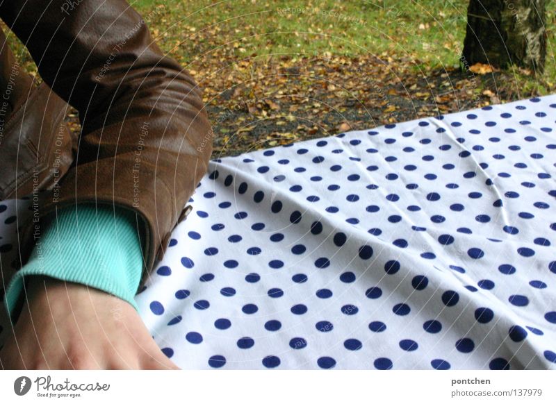 Forearm with cut arm lying on a dotted tablecloth on a table in the woods. Leather jacket. Picnic Relaxation Table Human being by hand Nature Autumn flaked