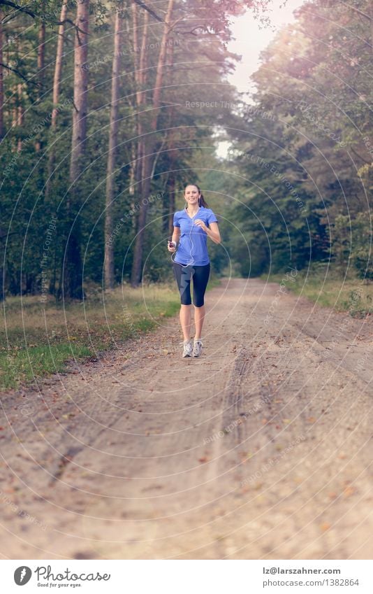 Athletic woman out jogging in a forest Lifestyle Body Music Sports Jogging Technology Girl Woman Adults 1 Human being 18 - 30 years Youth (Young adults) Nature