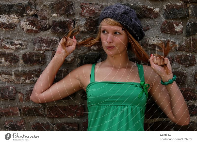 And now what? Woman Young woman Beautiful Green Long-haired Red-haired Cap T-shirt Facial expression Hand Bracelet Wall (barrier) Wall (building) Grimace