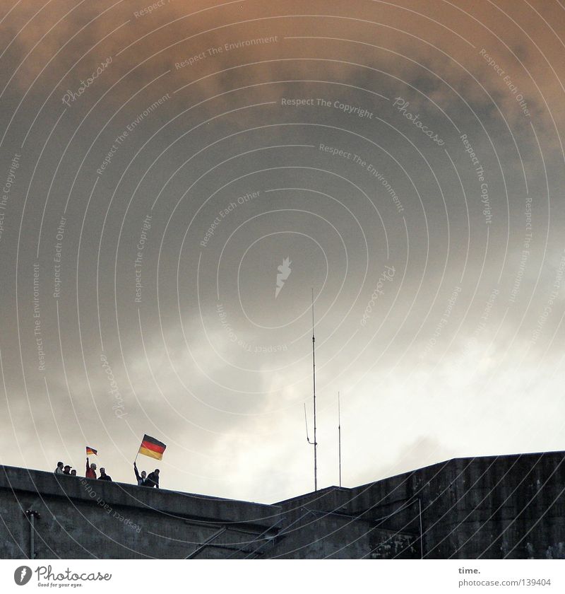 Two ensigns on a bunker Flag Outdoor festival Human being Antenna Strike Applause Roof Clouds Joy Relief Alcohol-fueled Ball sports Landmark Monument Dugout