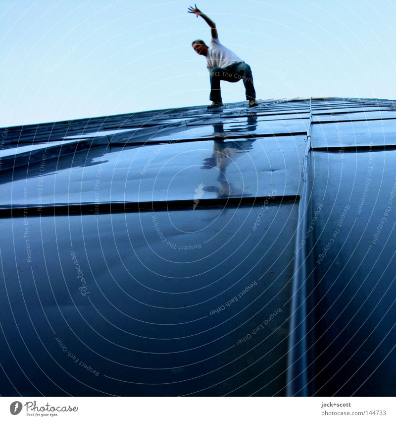 Man balances on a slope covered with metal Tall Above Blue Dexterity Body control Balance Risk of collapse Test of courage height Subdued colour Reflection