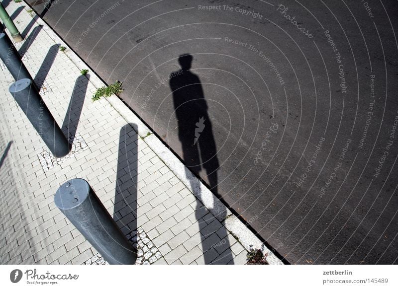 pile standing Street Traffic lane Sidewalk Cobbled pathway Pave Cobblestones Paving stone Bollard Pole Wooden stake Border Boundary Shadow Human being Stand