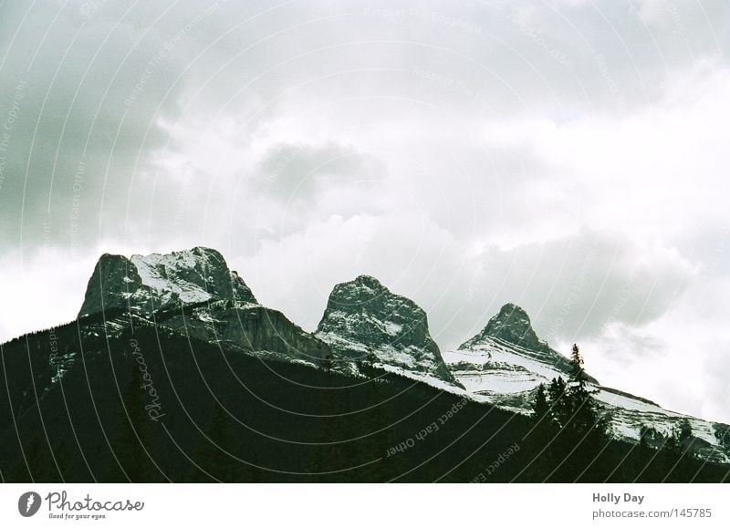 Three Sisters Mountain Peak Snow Virgin snow Clouds Bad weather Cold Dark Bright Converse Contrast Comfortless Tall Black White Storm Rain Threat Canada Sky