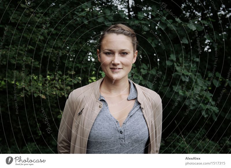 Young woman stands in front of a dark leafy background and looks happily into the camera pretty Contentment Vacation & Travel Youth (Young adults) Face