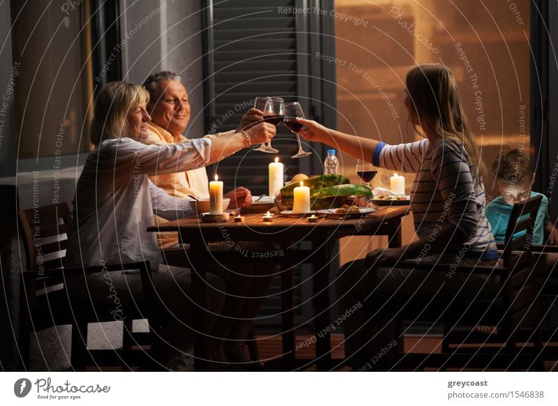 Family dinner outdoor in the backyard in quiet evening. Young woman and senior parents toasting with wine while child playing games Vegetable Dinner