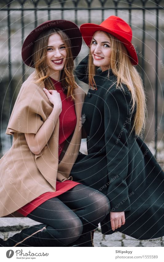 Two girls sitting on the bench and smile Lifestyle Joy Happy Beautiful Face Meeting To talk Human being Feminine Woman Adults Friendship Autumn Fashion Hat