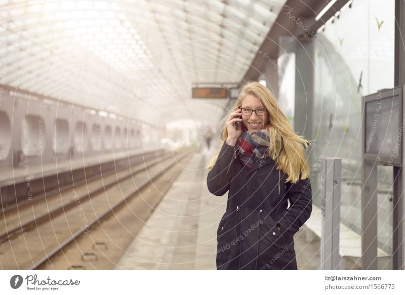 Young woman in black coat using mobile phone Happy Face Winter Telephone PDA Feminine Woman Adults 1 Human being 18 - 30 years Youth (Young adults) Transport