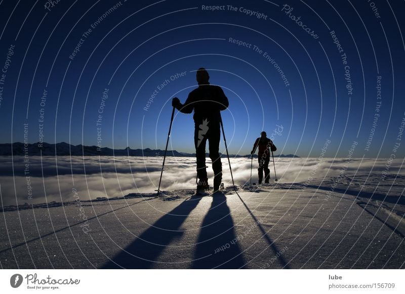 shadow play Shadow Ski tour Winter Winter sports Fog Sea of fog Clouds Skier Peak Mountain Climbing Snow Sky blue Nature Sports Playing