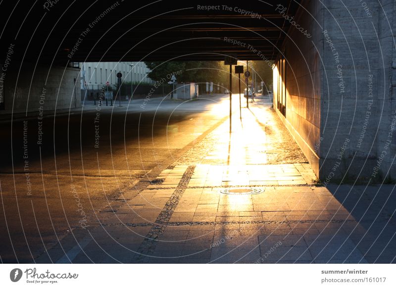 glowing footpath Sunset Dusk Underpass Bridge Berlin Town Nature Summer Warmth Sidewalk Street Cobblestones Street sign Stop (public transport) Orange Flashy