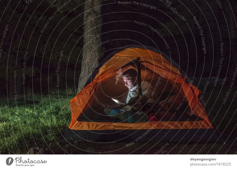 Man watching his smartphone in a tent Lifestyle Happy Vacation & Travel Adventure Camping Summer Hiking Telephone PDA Human being Adults Friendship Forest Dark