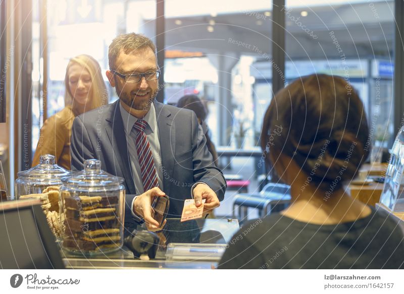 Male customer making a payment in a shop Shopping Happy Money Man Adults 4 Human being 18 - 30 years Youth (Young adults) 30 - 45 years Suit Tie Beard Paying