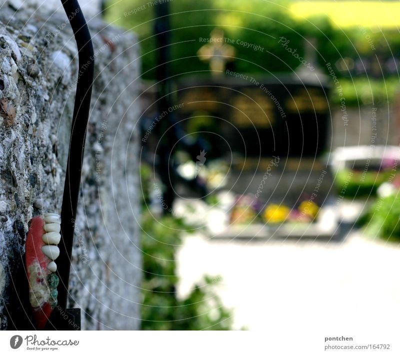 A lost set of teeth attached to a cable on a wall in the cemetery. Found. Aging, death. Macabre gravestones and crosses in the background Funeral service Sign