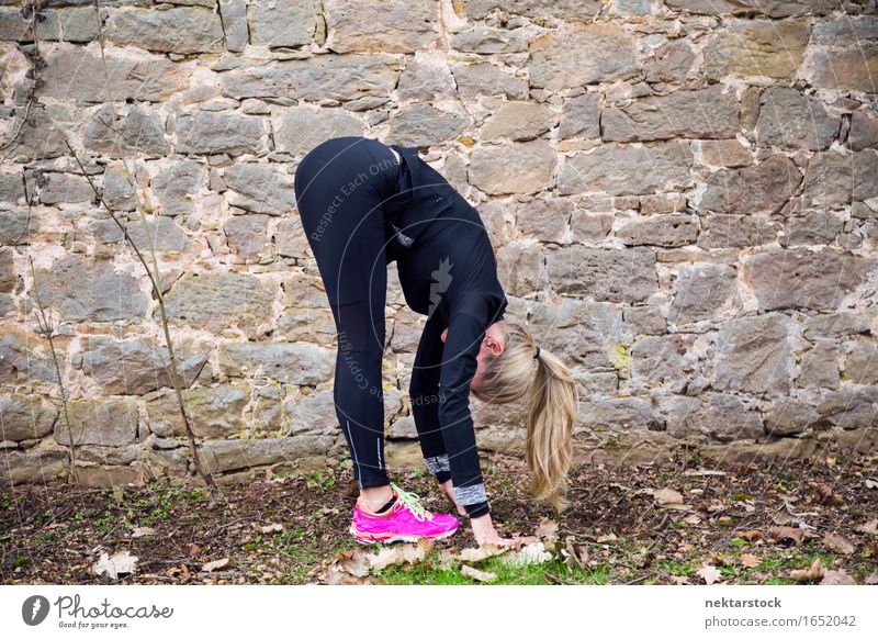 Woman stretching her body in front of ancient wall in park Lifestyle Happy Body Wellness Sports Human being Adults Park Stone Fitness Smiling Athletic