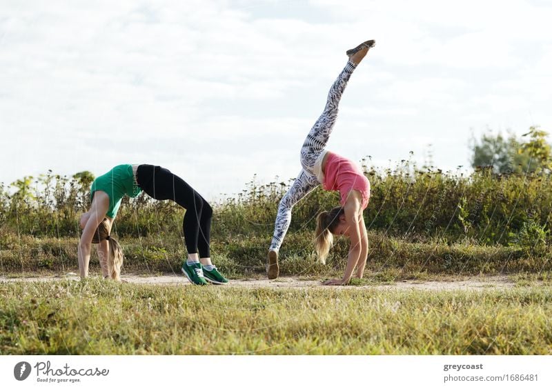 Two young girls training together outdoors: stretching exercises Fitness Sports Training Human being Girl Young woman Youth (Young adults) Woman Adults