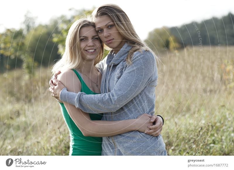 Two loving sisters comforting each other hugging each other in a close embrace as they stand outdoors in the countryside Lifestyle Happy Beautiful