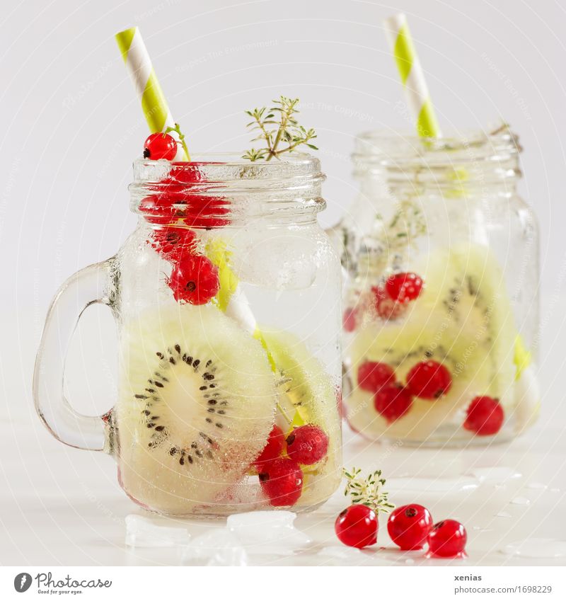 two glasses of soft drink with kiwi and currant in front of a light background Cold drink Fruit Kiwifruit Redcurrant Thyme Food Ice cube Vitamin Diet Beverage