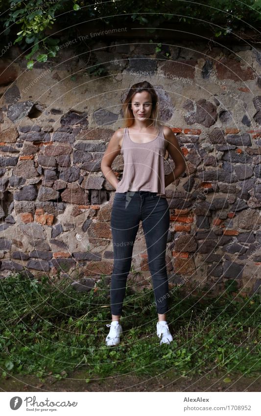 Attracted Joy Beautiful Athletic Young woman Youth (Young adults) 18 - 30 years Adults Landscape Ivy Wall (barrier) Wall (building) Jeans Top Sneakers Blonde