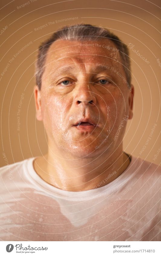 Tired looking hot perspiring middle-aged man after a workout, closeup head and shoulders portrait looking directly at the camera Face Health care Wellness