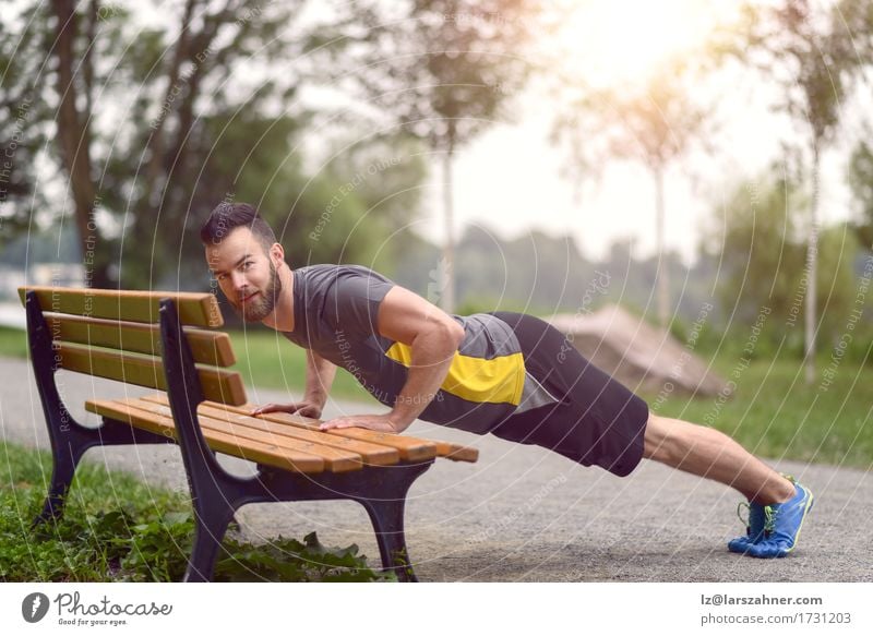 Young man working out doing push-ups on a wooden park bench Lifestyle Body Face Sports Man Adults 1 Human being 18 - 30 years Youth (Young adults) Park Beard