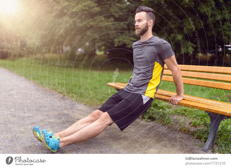 Young man exercising in a park Lifestyle Body Sports Man Adults 1 Human being Nature Park Beard Wood Fitness Athletic Modern Action Balance bearded Bench