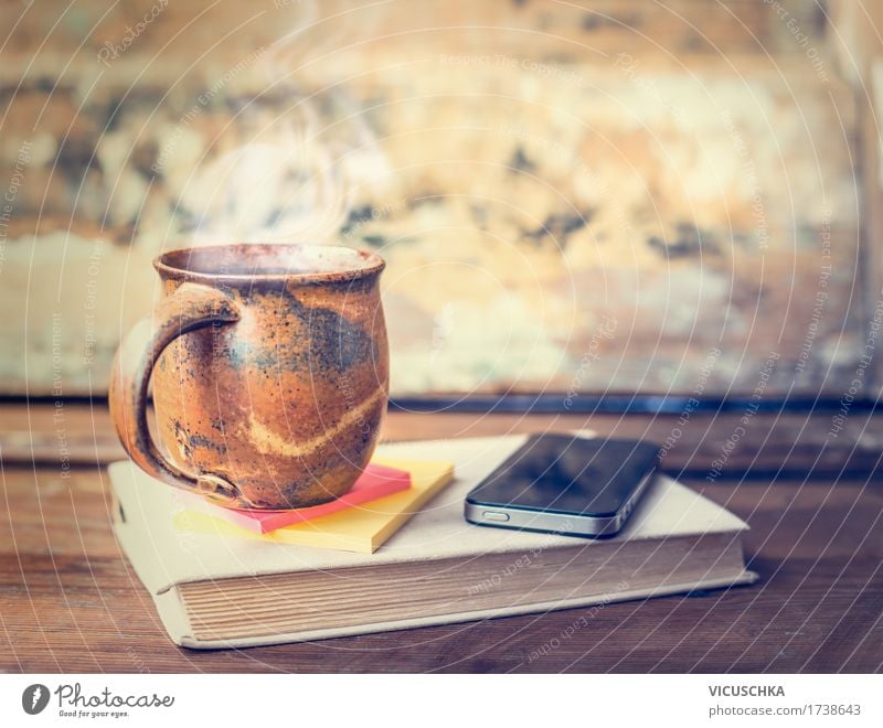 Cup with hot drink on book with smart phone Beverage Hot drink Coffee Tea Lifestyle Style Design Living or residing Table Cellphone PDA Retro Vintage Steam Book