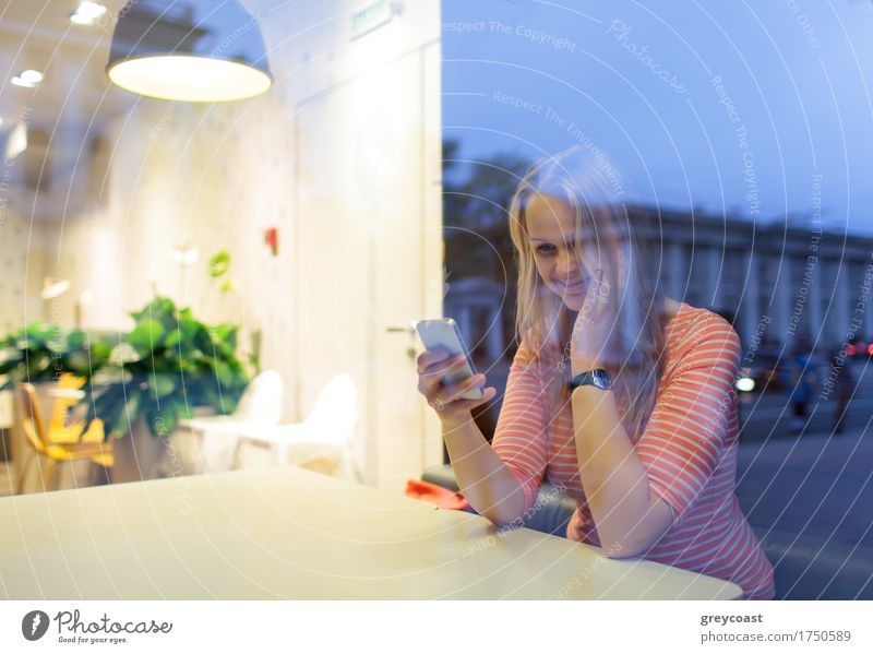 Happy woman in cafeteria reading or typing sms. View through the glass with city reflection Restaurant Telephone PDA Young woman Youth (Young adults) 1