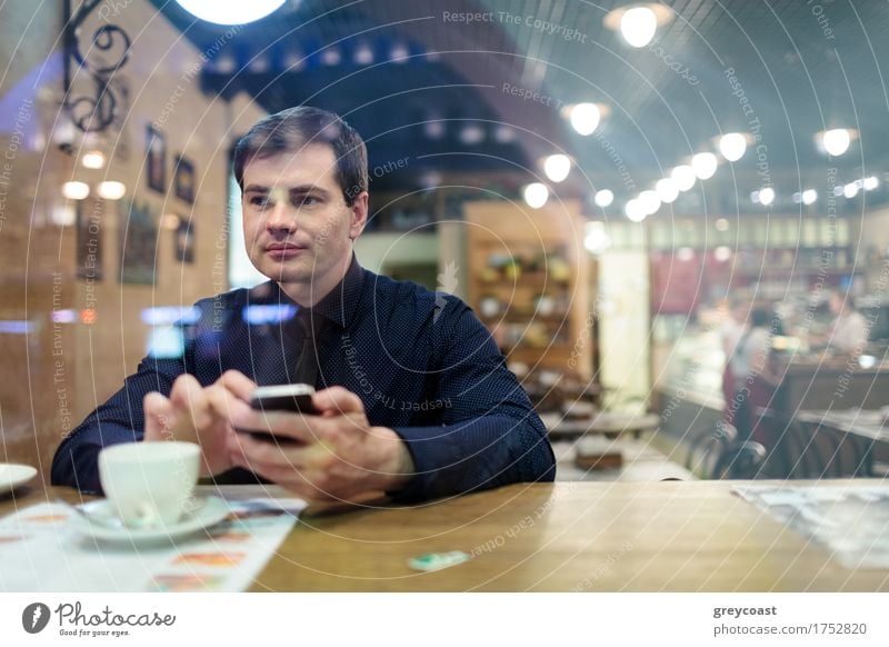 Man at the table texting and drinking a cup of coffee in the cafe Coffee Restaurant Telephone PDA Homosexual Young man Youth (Young adults) 1 Human being