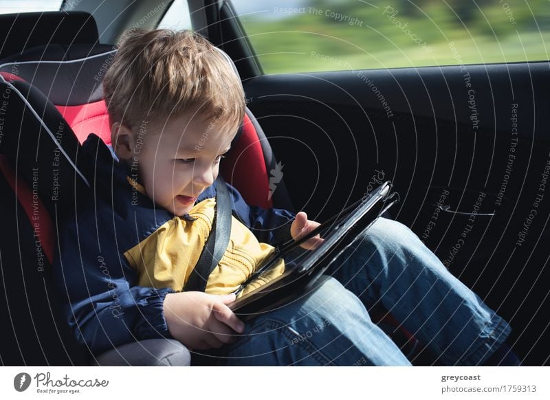 Excited little boy in the car playing with touchpad sitting in child safety seat Joy Happy Playing Vacation & Travel Trip Child Computer Boy (child) 1