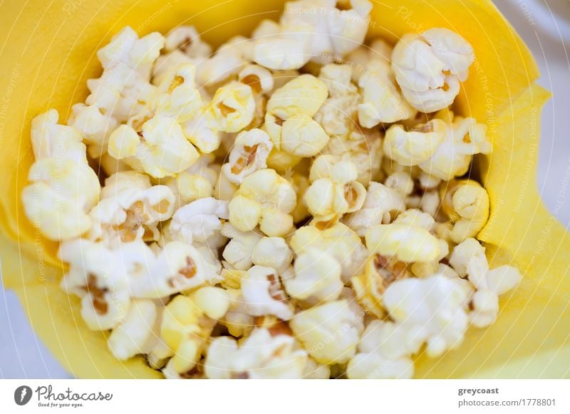 High angle close-up shot of tasty popcorn in yellow paper bag Cinema Paper Delicious Yellow Popcorn food Meal Paper bag Snack Tasty movie hign angle Horizontal