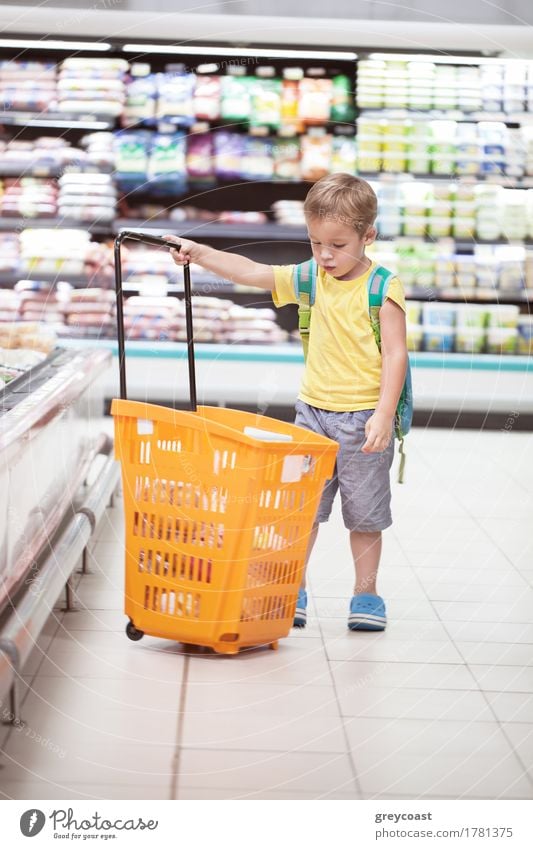 Little boy in the supermarket looking at big full shopping cart. Child going shopping alone Shopping Human being Boy (child) 1 3 - 8 years Infancy