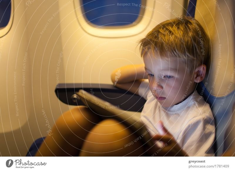 Little boy sitting in the plane and playing on touch pad. Traveling by air Joy Leisure and hobbies Playing Vacation & Travel Trip Child Computer Boy (child) 1